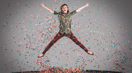 Woman jumping on trampoline with confetti